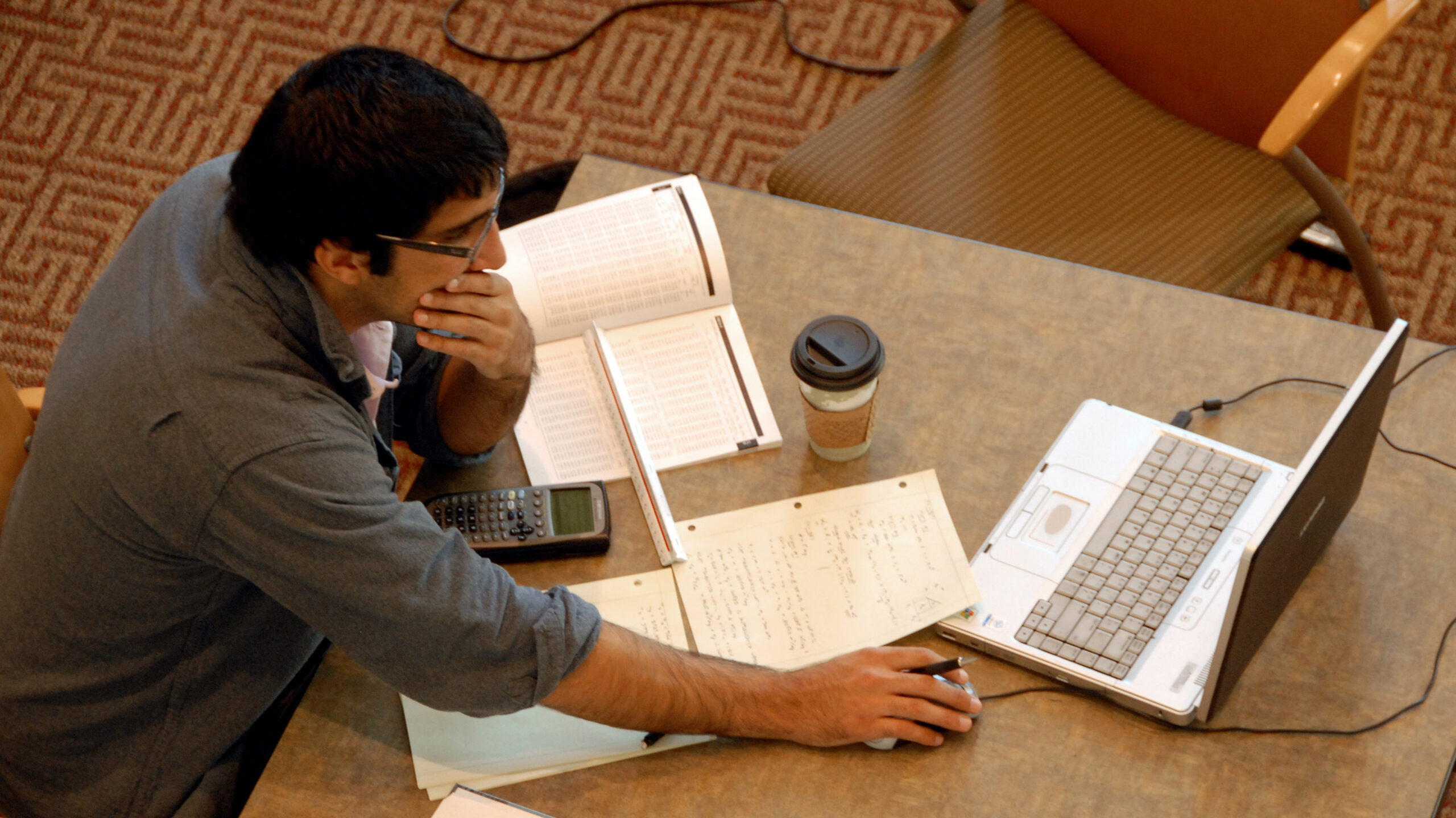 Student studying with open books and a laptop.